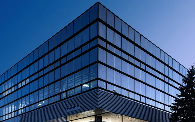 Corner of a modern glass office building under a deep blue sky