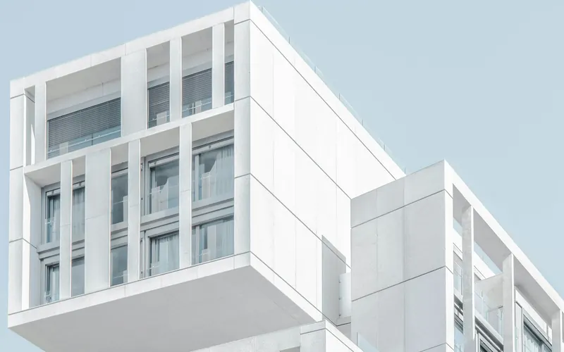 Modern white multi-storey facility building against a pale sky